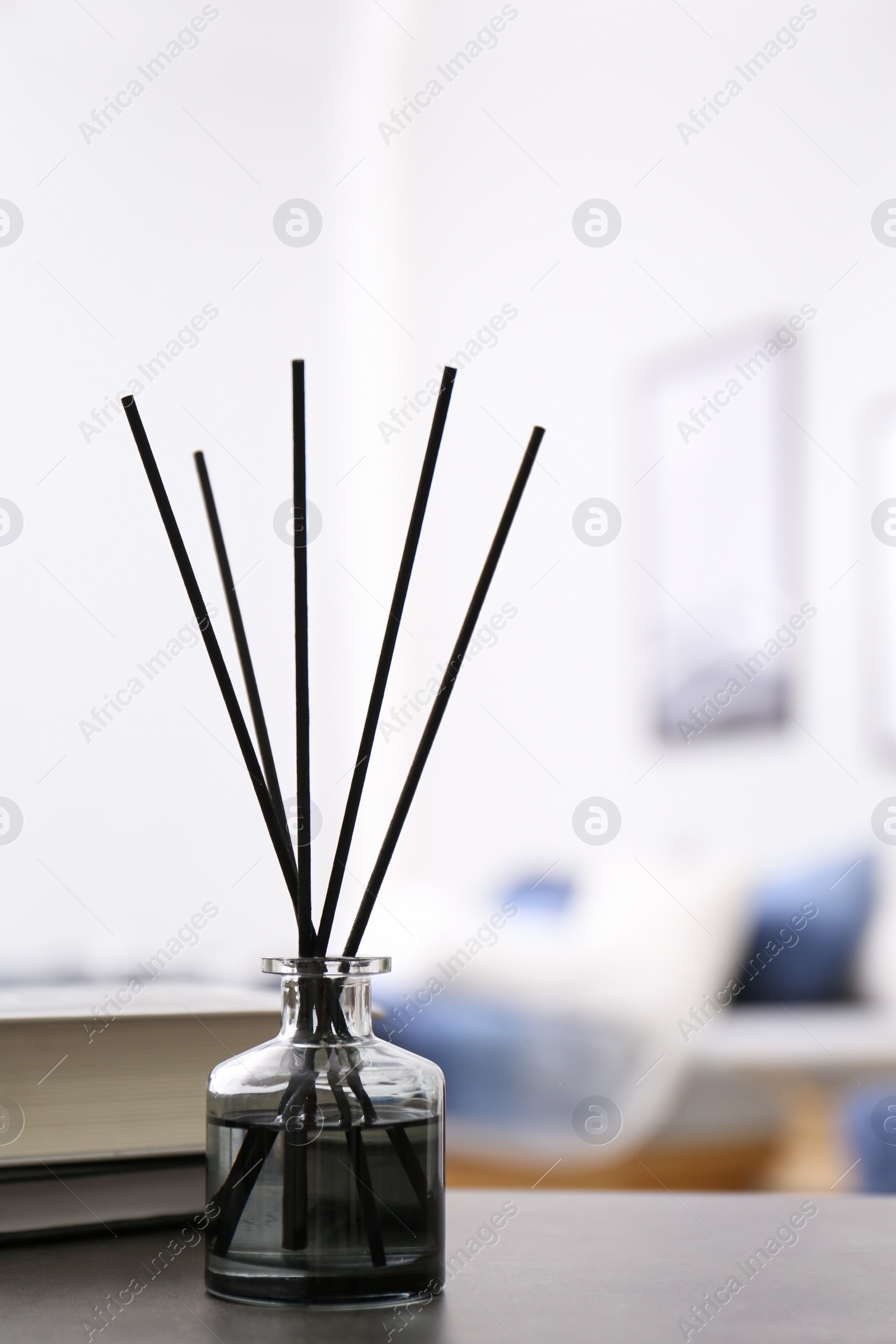 Photo of Aromatic reed air freshener and books on table in room