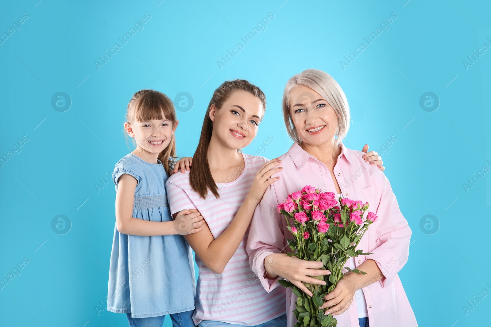Photo of Beautiful mature lady, daughter and grandchild with flowers on color background. Happy Women's Day