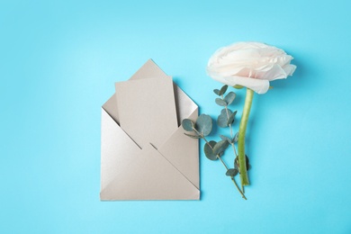 Flat lay composition with beautiful ranunculus flower and card in envelope on color background. Space for text