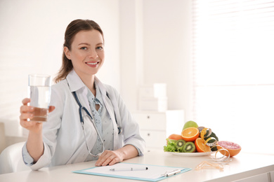 Photo of Nutritionist with glass of water at desk in office. Space for text