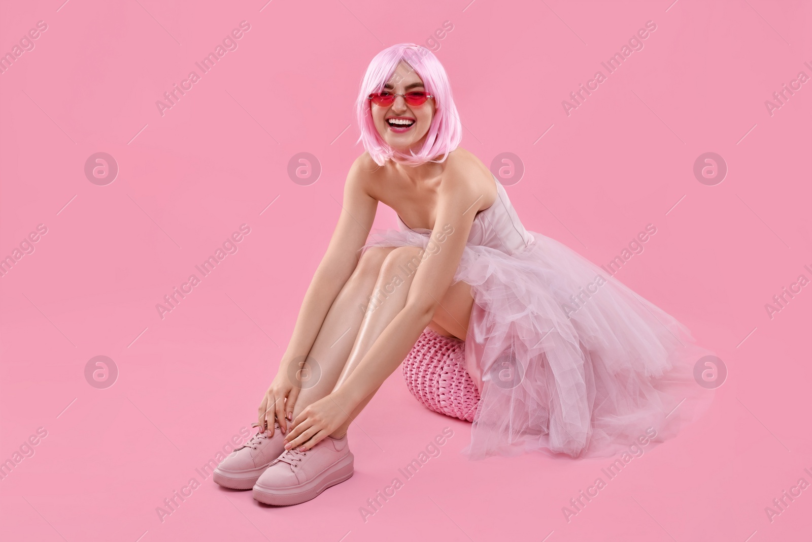 Photo of Pink look. Beautiful woman in dress and wig on color background