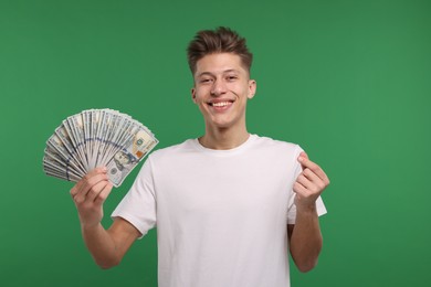 Photo of Happy man with dollar banknotes showing money gesture on green background