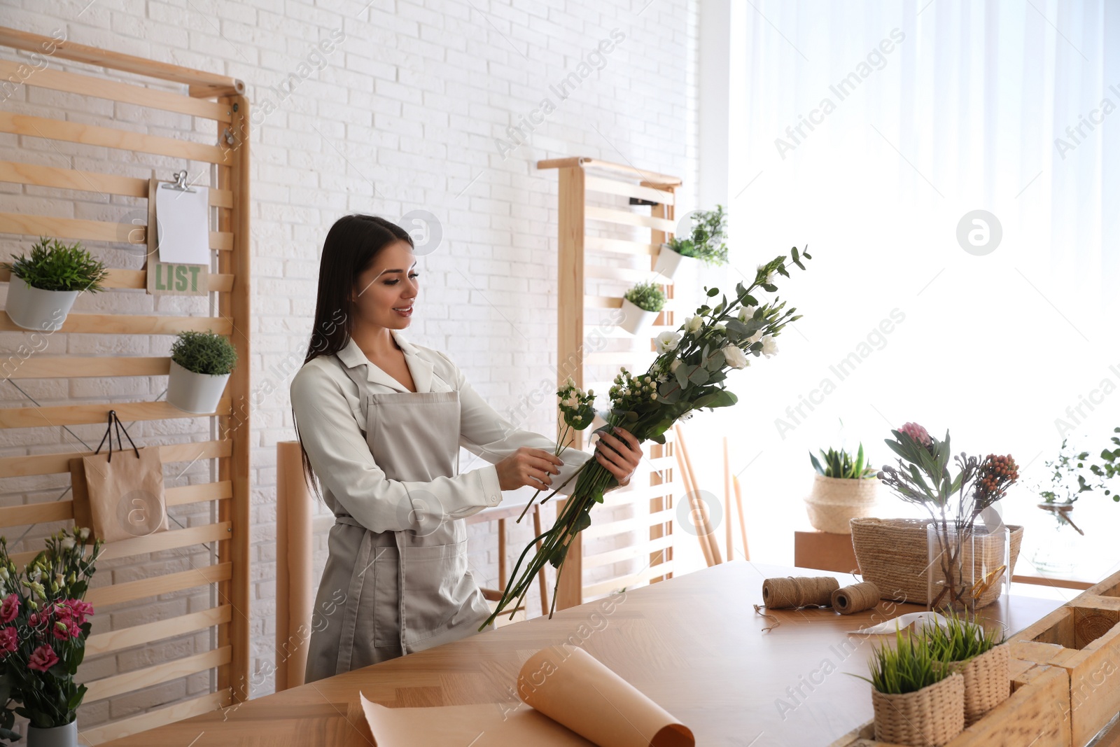 Photo of Florist making beautiful bouquet at table in workshop