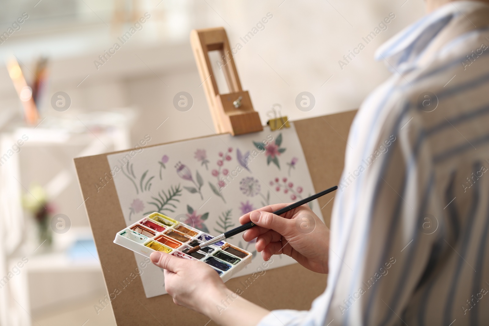 Photo of Woman painting flowers with watercolors in workshop, closeup