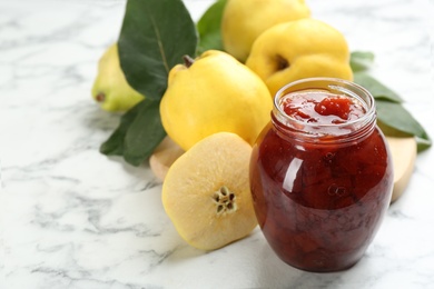 Photo of Delicious quince jam and fruits on white marble table, closeup