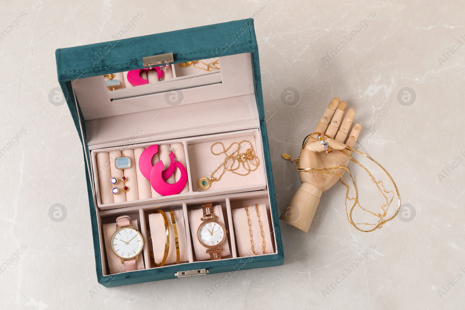 Photo of Jewelry box with many different accessories and mannequin hand on light grey table, flat lay