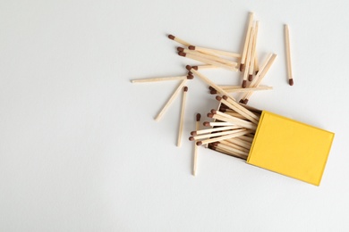 Photo of Cardboard box and matches on light background, top view. Space for design