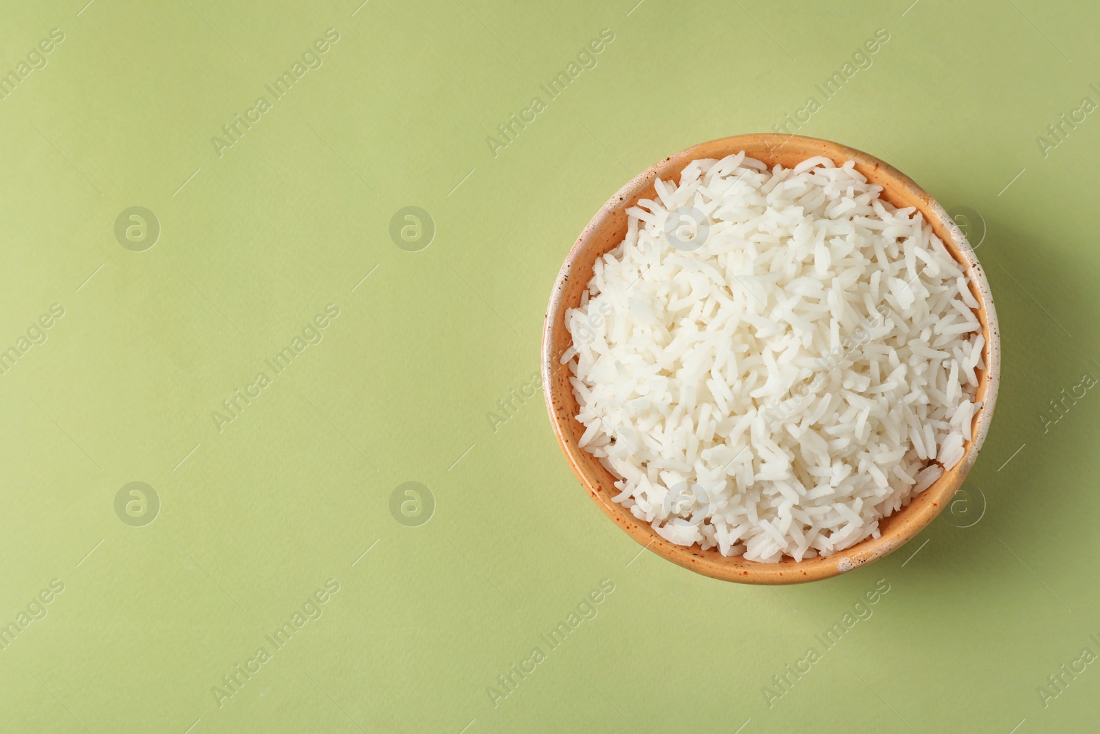 Photo of Bowl of tasty cooked rice on color background, top view. Space for text