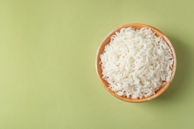 Bowl of tasty cooked rice on color background, top view. Space for text