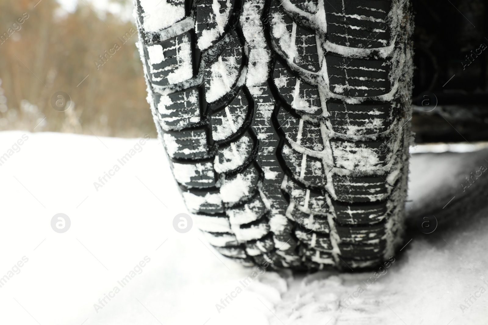 Photo of Car with winter tires on snowy road, closeup of wheel