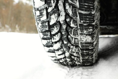 Photo of Car with winter tires on snowy road, closeup of wheel