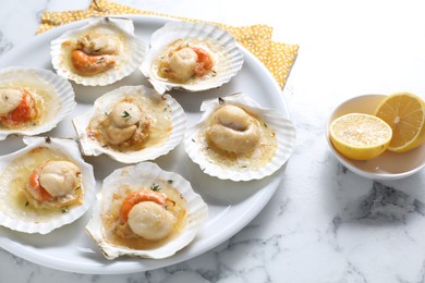 Photo of Fried scallops in shells and lemon on white marble table