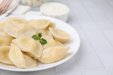 Photo of Plate of delicious dumplings (varenyky) with cottage cheese on white table, closeup