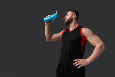 Photo of Young man with muscular body holding shaker of protein on grey background. Space for text