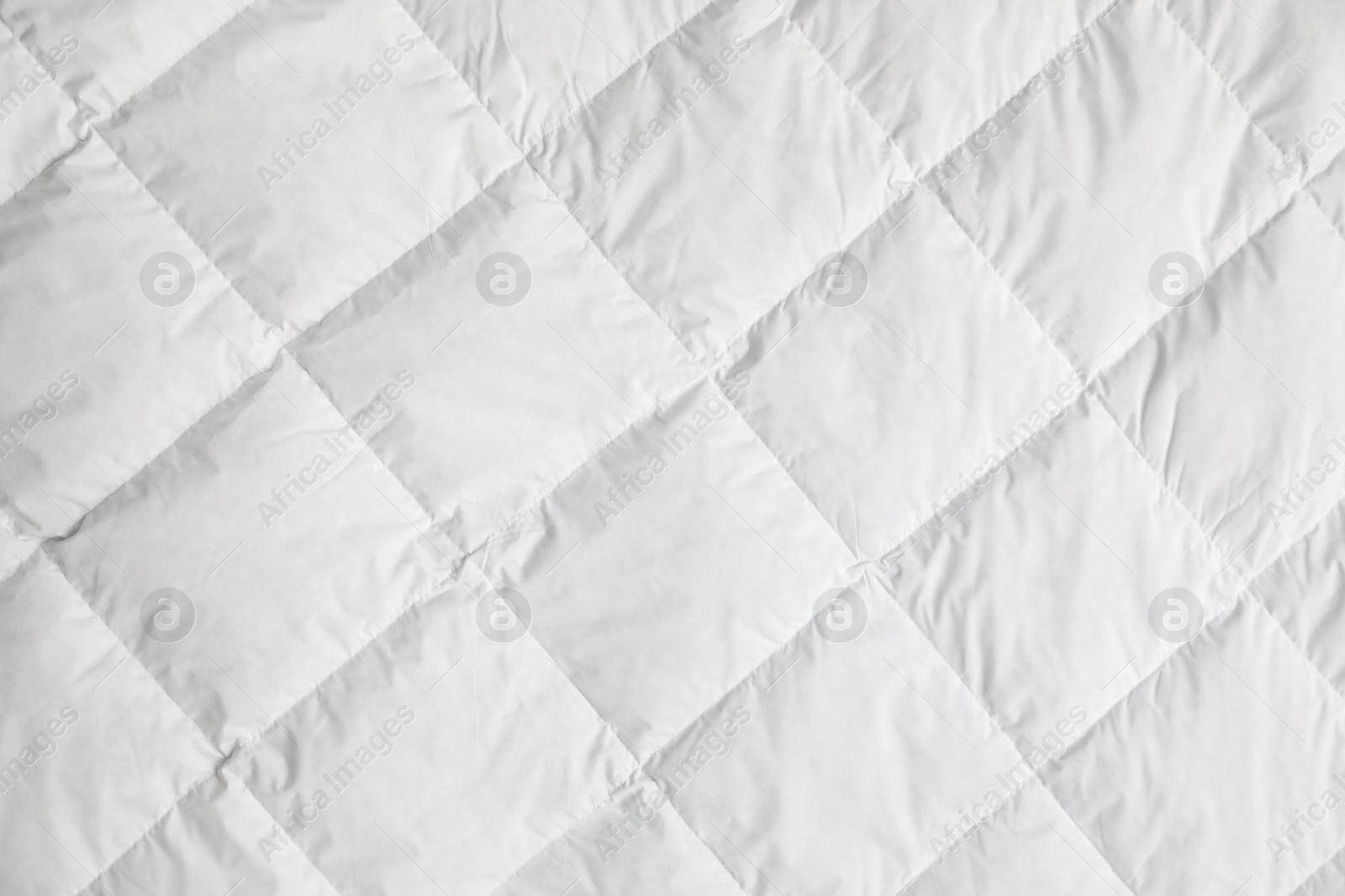 Photo of Soft quilted blanket as background, top view