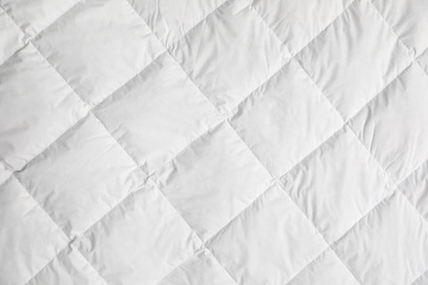 Photo of Soft quilted blanket as background, top view
