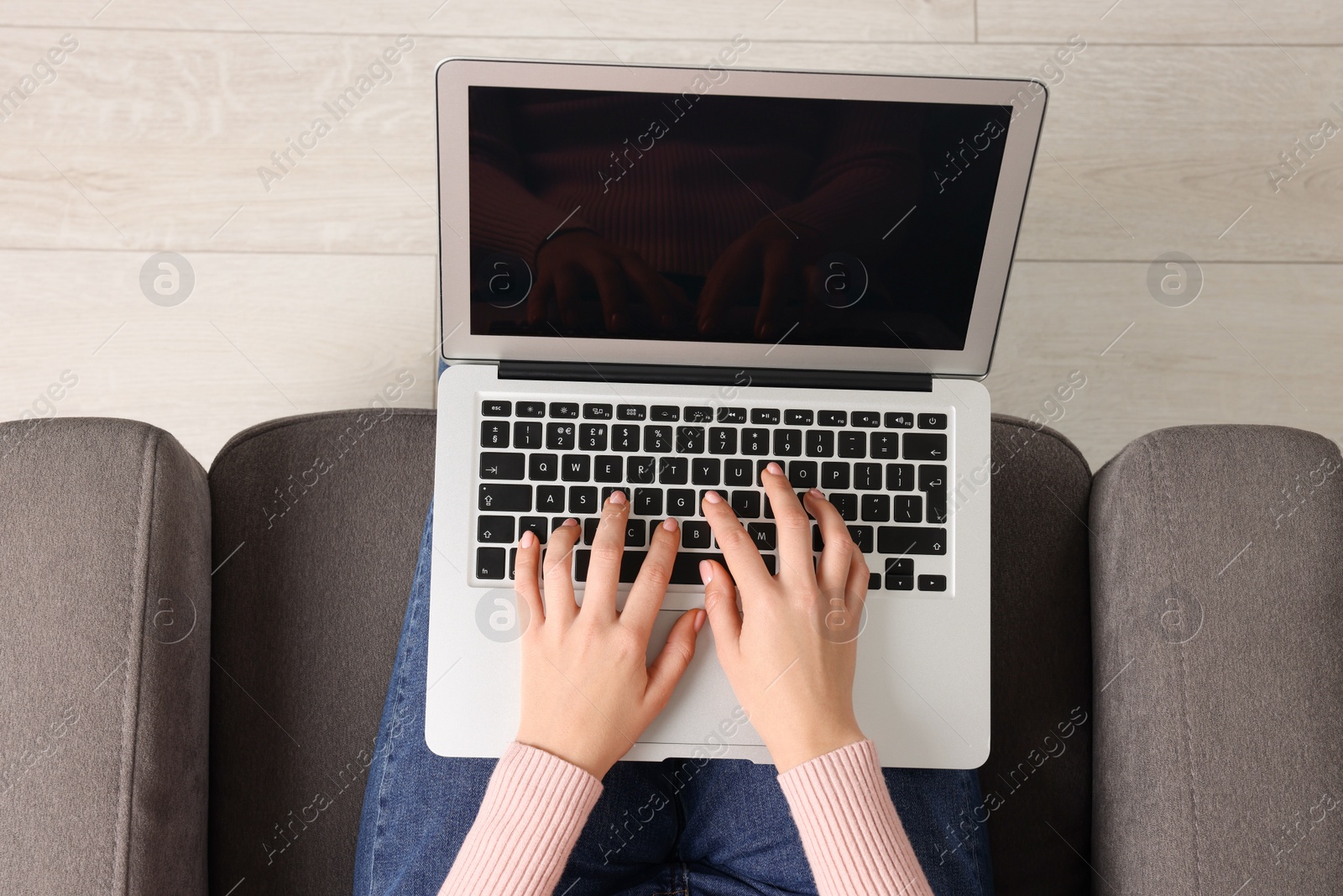 Photo of Woman working with laptop in armchair, top view