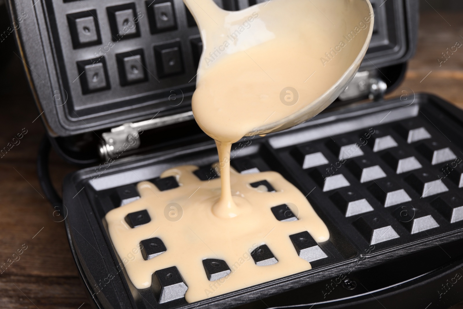 Photo of Pouring dough onto Belgian waffle maker, closeup