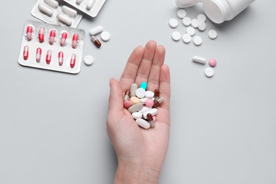 Photo of Woman holding colorful antidepressants on grey background, top view