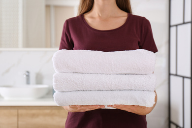 Photo of Woman holding fresh towels in bathroom, closeup