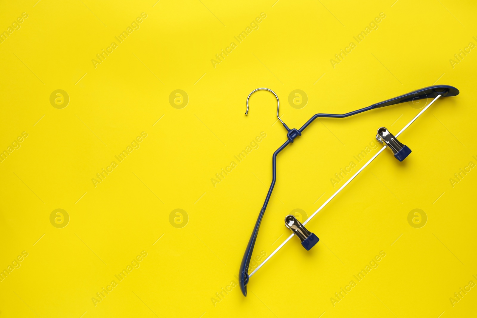 Photo of Empty hanger on yellow background, top view. Space for text