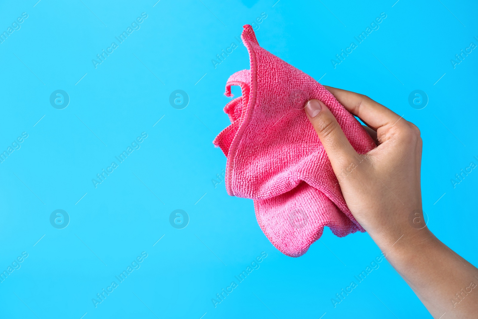 Photo of Woman holding microfiber cloth on light blue background, closeup. Space for text