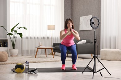 Happy sports blogger streaming online fitness lesson with smartphone at home