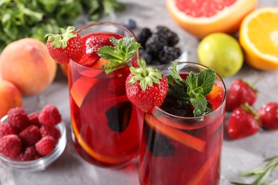 Photo of Delicious refreshing sangria with fresh fruits and berries on light grey table, closeup