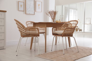 Photo of Dining room interior with wooden table and wicker chairs