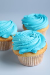 Photo of Delicious cupcakes with bright cream on light background, closeup