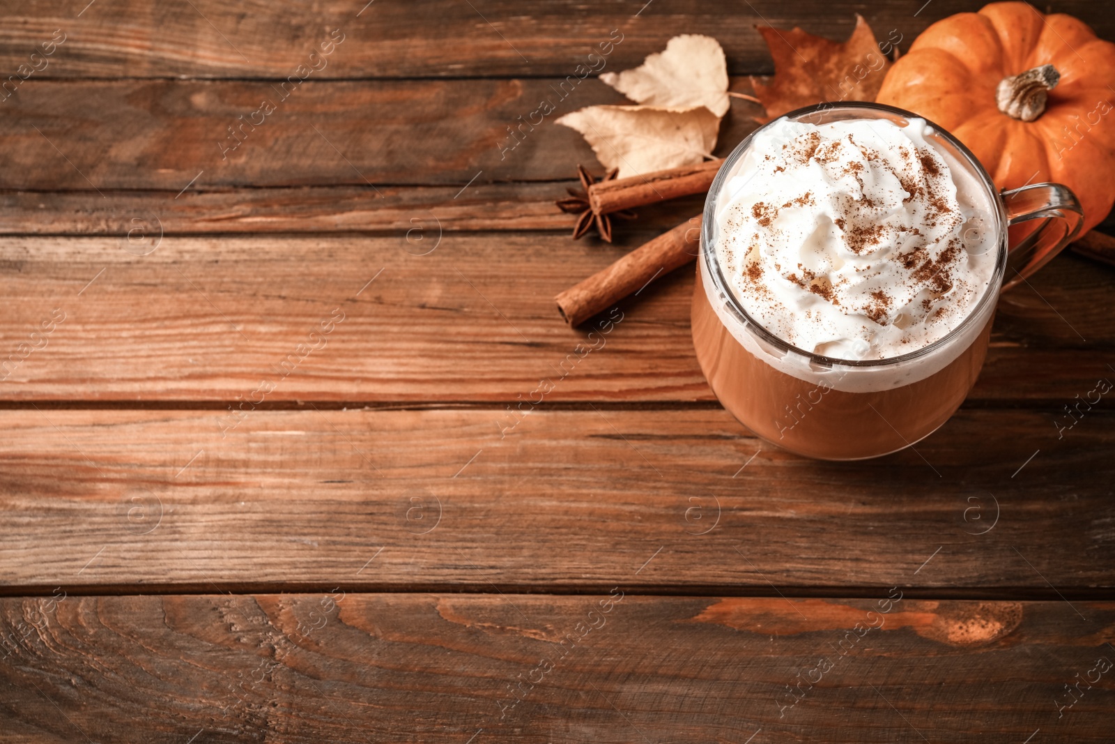 Photo of Delicious pumpkin latte on wooden table, above view. Space for text