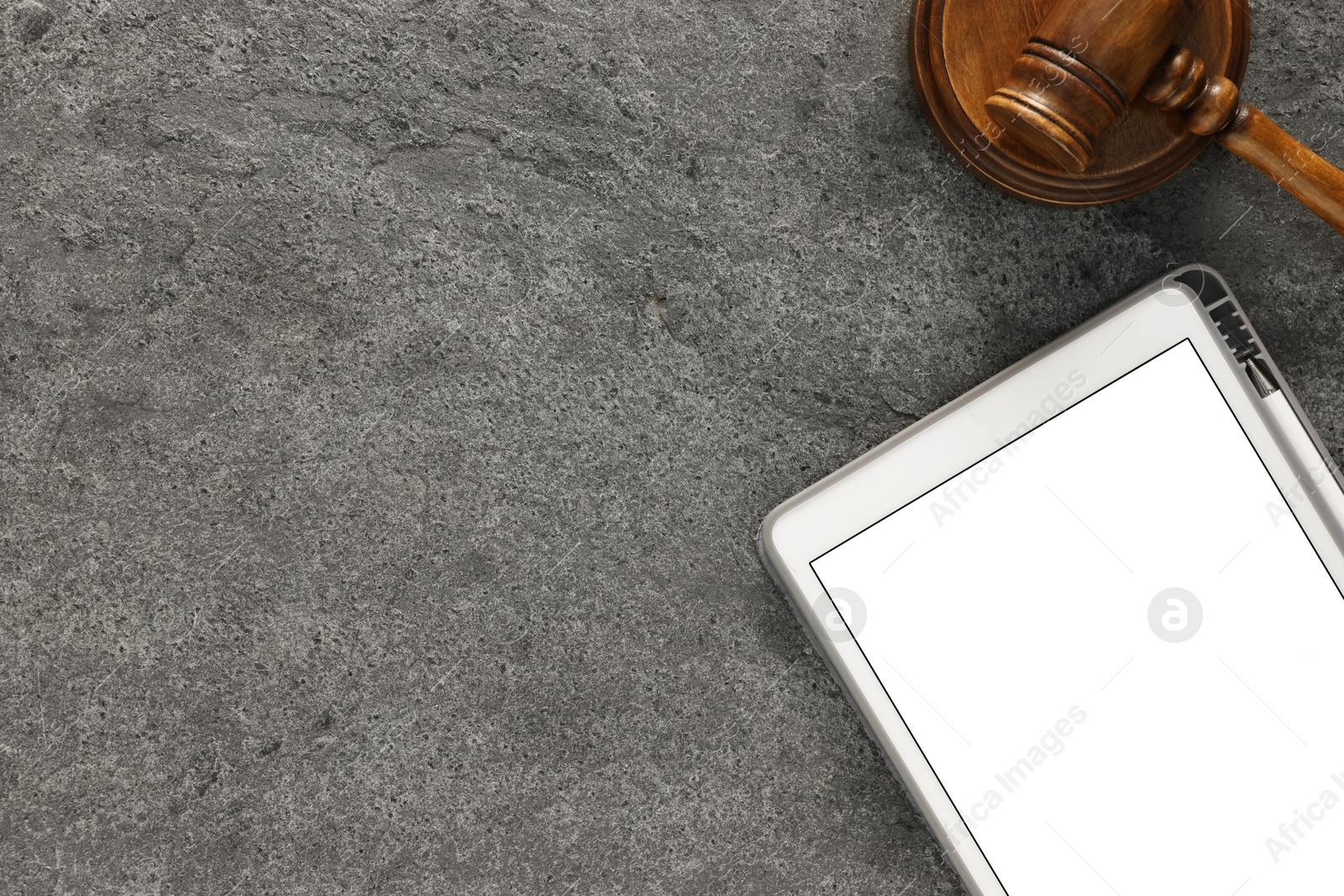 Photo of Modern tablet and gavel on gray textured table, flat lay. Space for text