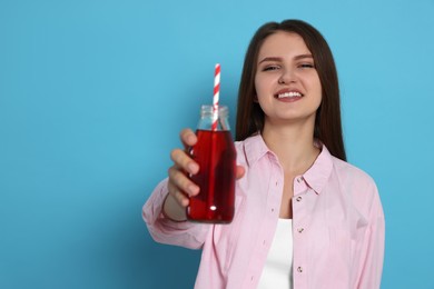 Photo of Beautiful young woman with glass bottle of juice on light blue background. Space for text