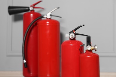 Red fire extinguishers near grey wall, selective focus