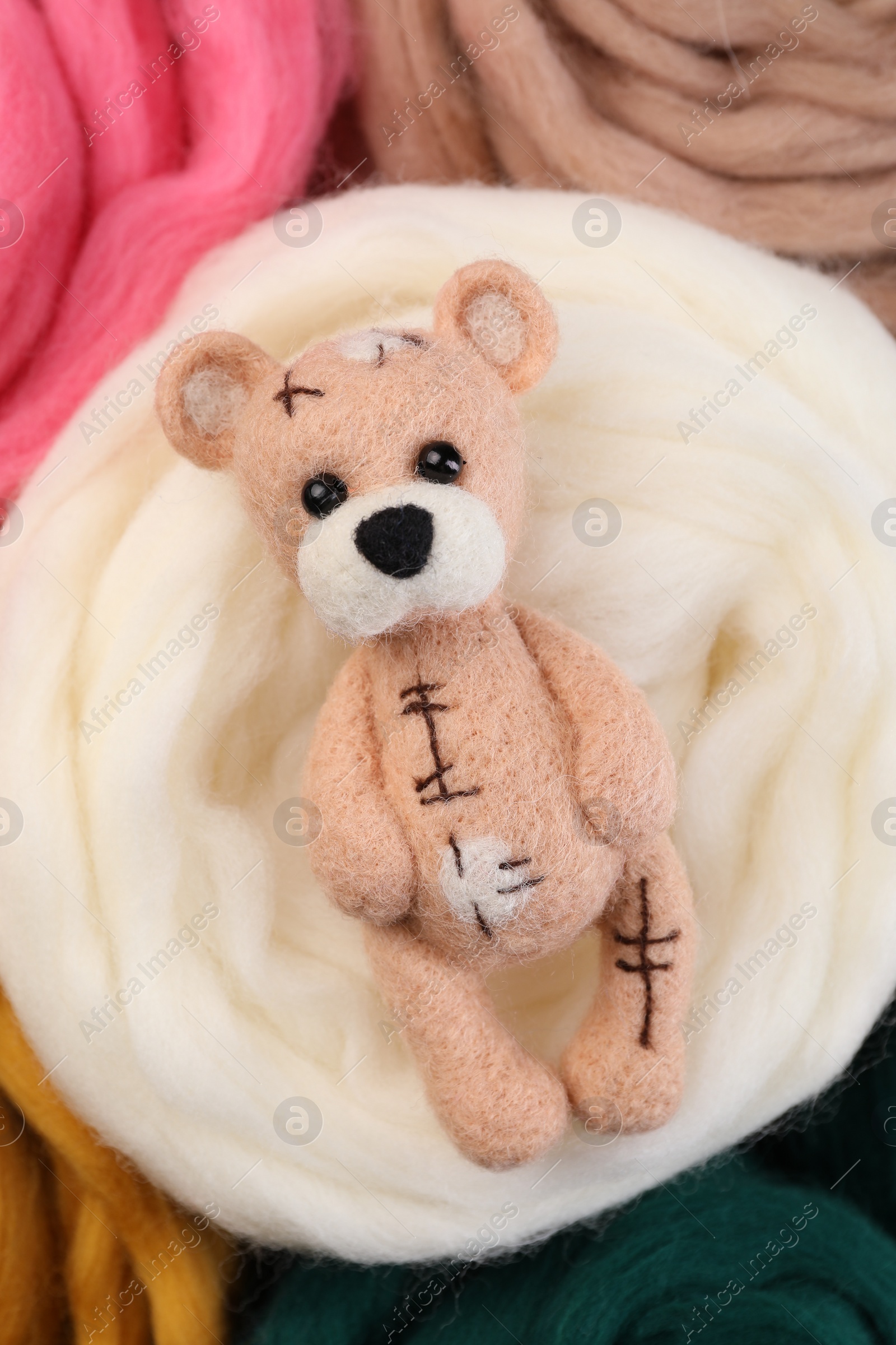 Photo of Felted bear on colorful wool, top view