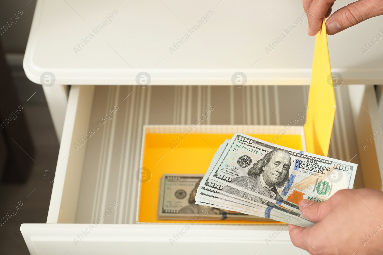 Photo of Man hiding dollar banknotes in cabinet indoors, closeup. Money savings