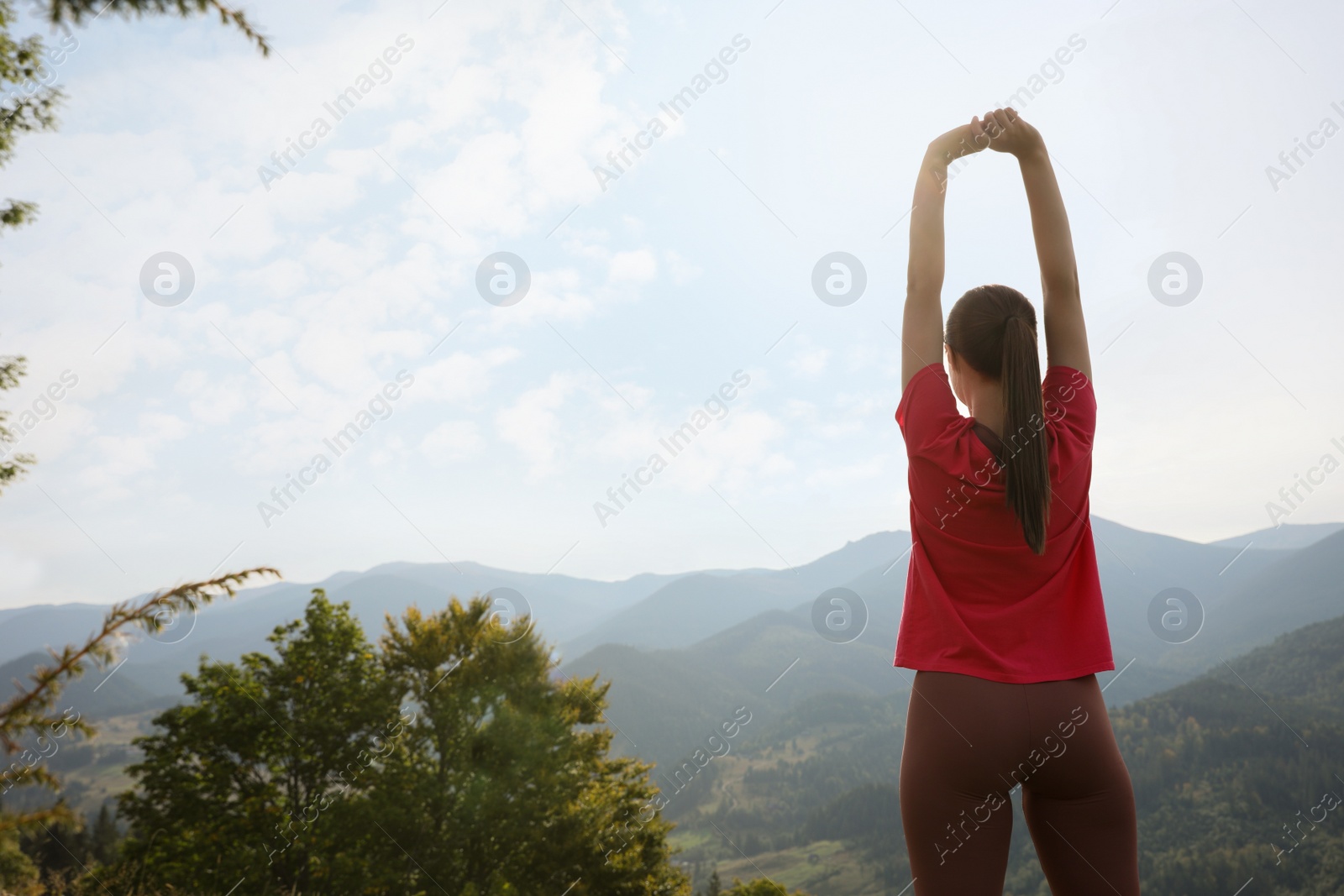 Photo of Woman doing morning exercise in mountains, back view. Space for text