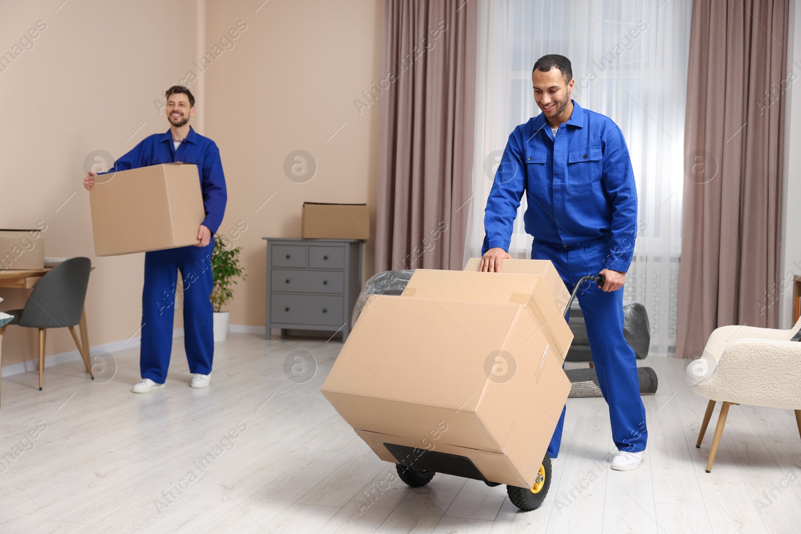 Photo of Male movers with cardboard boxes in new house