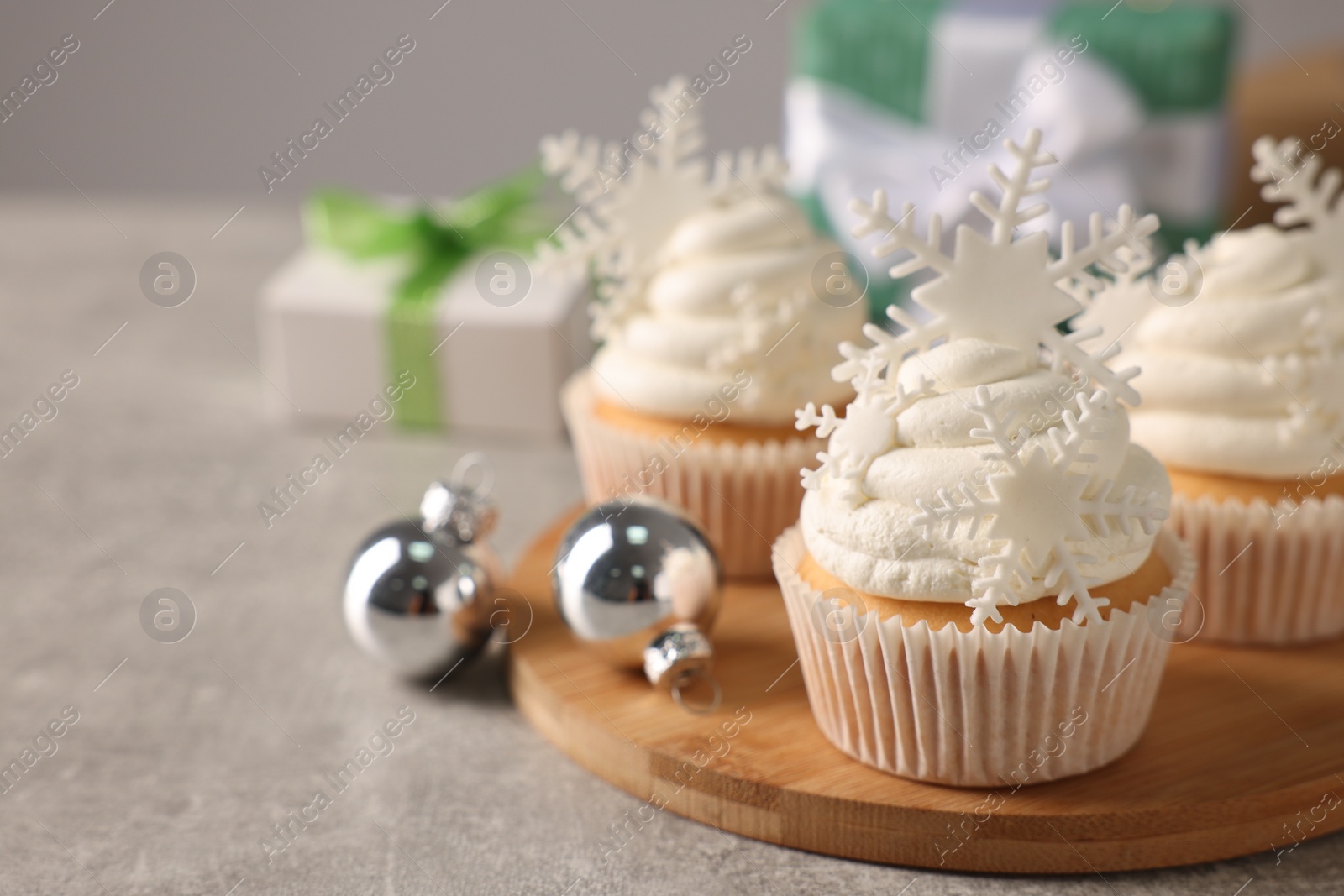 Photo of Tasty Christmas cupcakes with snowflakes on grey table. Space for text