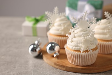 Tasty Christmas cupcakes with snowflakes on grey table. Space for text