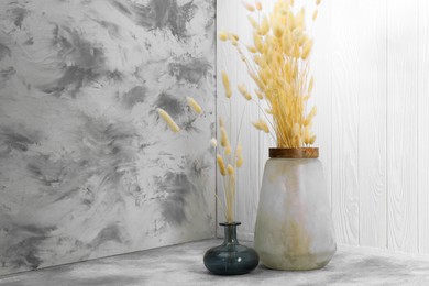Photo of Vases with beautiful dry flowers and double-sided backdrops in photo studio