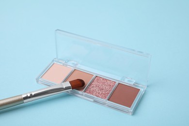 Photo of Beautiful eye shadow palette and brush on light blue background