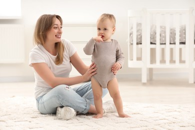Photo of Mother with her little son on rug at home