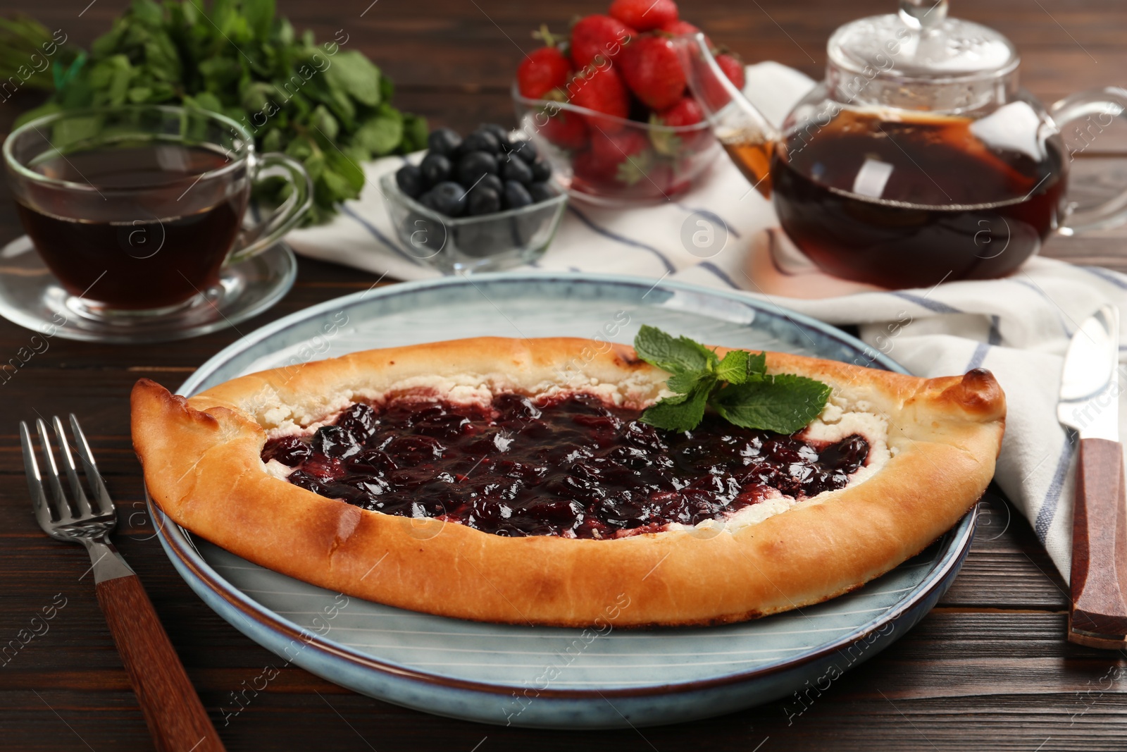 Photo of Delicious sweet cottage cheese pastry with cherry jam served on wooden table