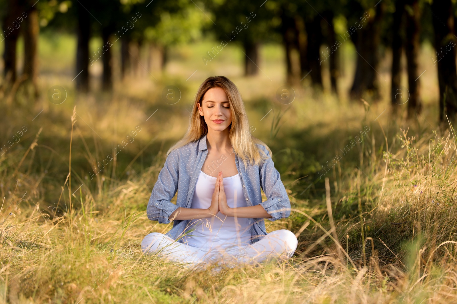 Photo of Young woman meditating in forest on sunny day