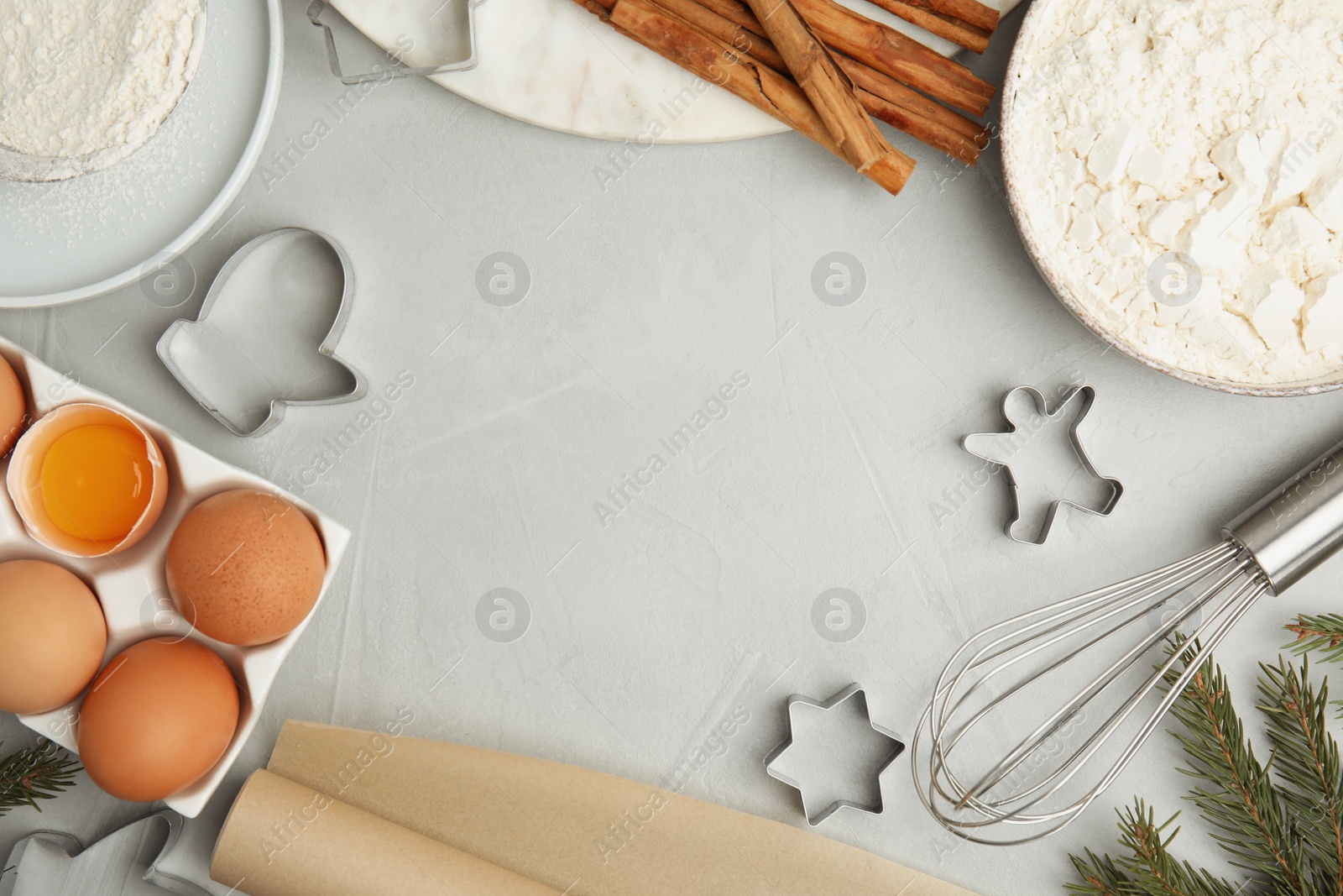 Photo of Flat lay composition with cookie cutters and ingredients on light grey table, space for text. Christmas biscuits