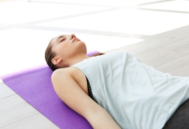 Photo of Young woman in sportswear practicing yoga indoors