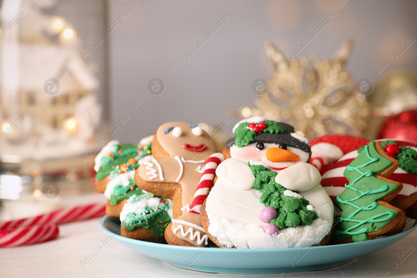 Photo of Sweet Christmas cookies on white table against blurred festive lights, closeup