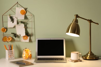 Photo of Stylish workplace with handmade decor made of dry orange slices and notes