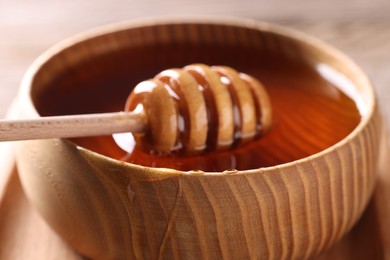 Photo of Delicious honey in wooden bowl and dipper, closeup